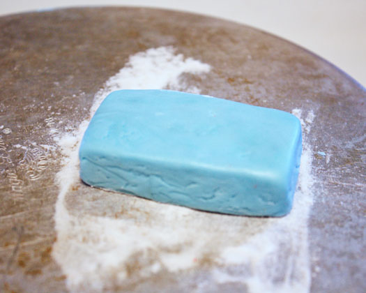 Take a ball of blue fondant and cut/shape it into a "base" for the tractor